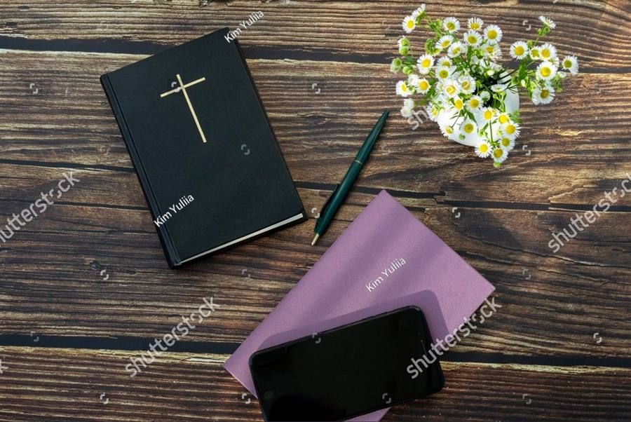 A Bible, a notebook and a pen on a wooden table