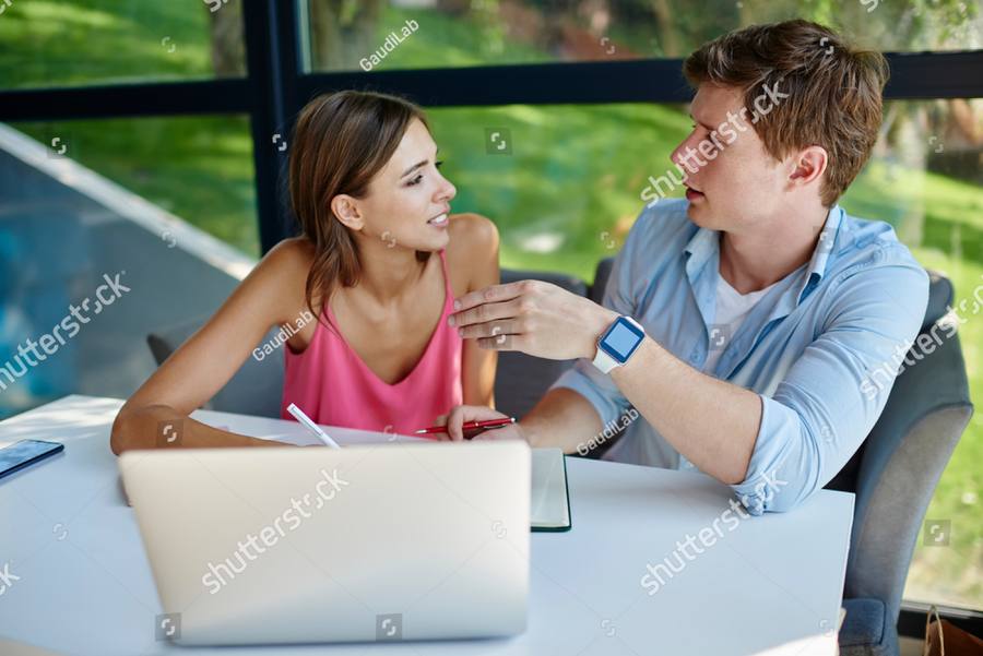 Two people talking across a table by a window